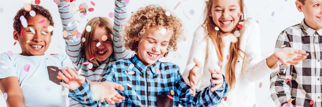 Happy kids throwing colorful confetti in a room