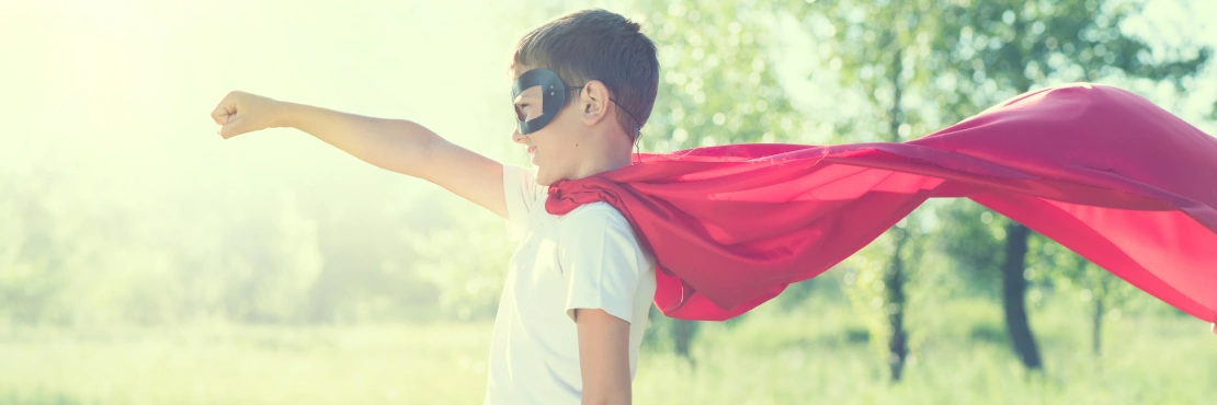Super Hero Kid hat Spaß im Freien. Superhero kleiner Boy auf unscharfem Naturhintergrund